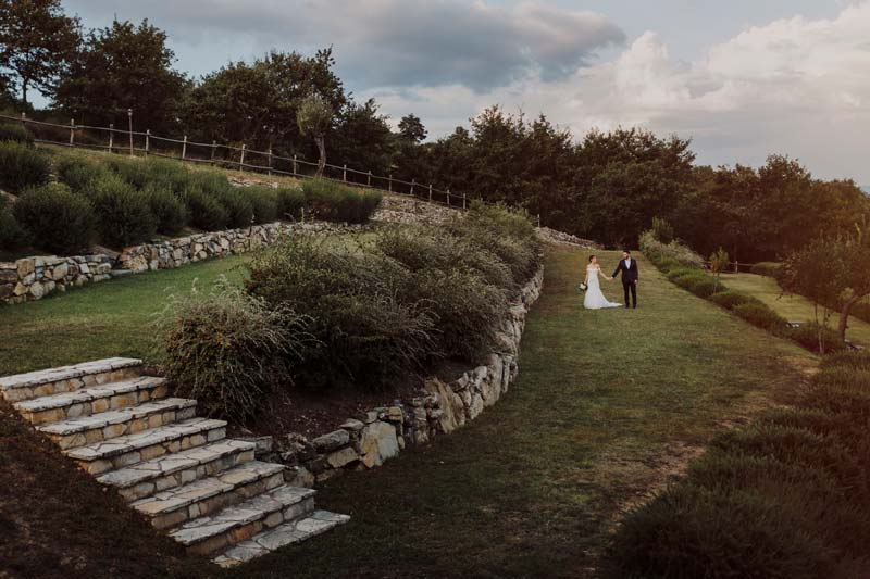 In questa foto una coppia di sposi fotografata mentre passeggia su uno degli splendidi prati verdi all'inglese del borgo per matrimoni in Umbria Spao Borgo San Pietro