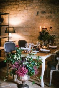 In questa foto un grande vaso di astilbe, felce e piante verdi posto ai piedi di un tavolo allestito per un matrimonio country chic a spao borgo san pietro