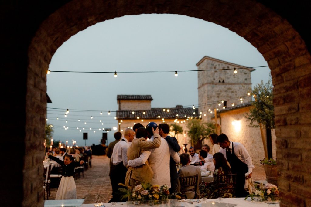 In questa foto lo sposo abbracciato ai suoi amici è fotografato di spalle, con vista sull'area di Spao Borgo San Pietro allestita per il ricevimento di nozze